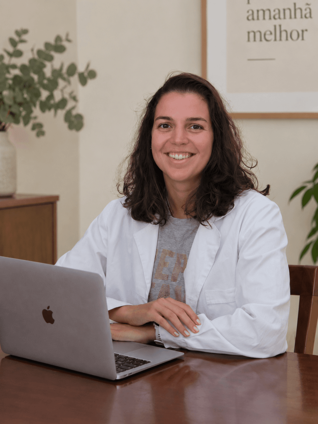 Marta Lucas Santos, nutricionista, sentada à secretária em frente ao portátil, num consultório claro.